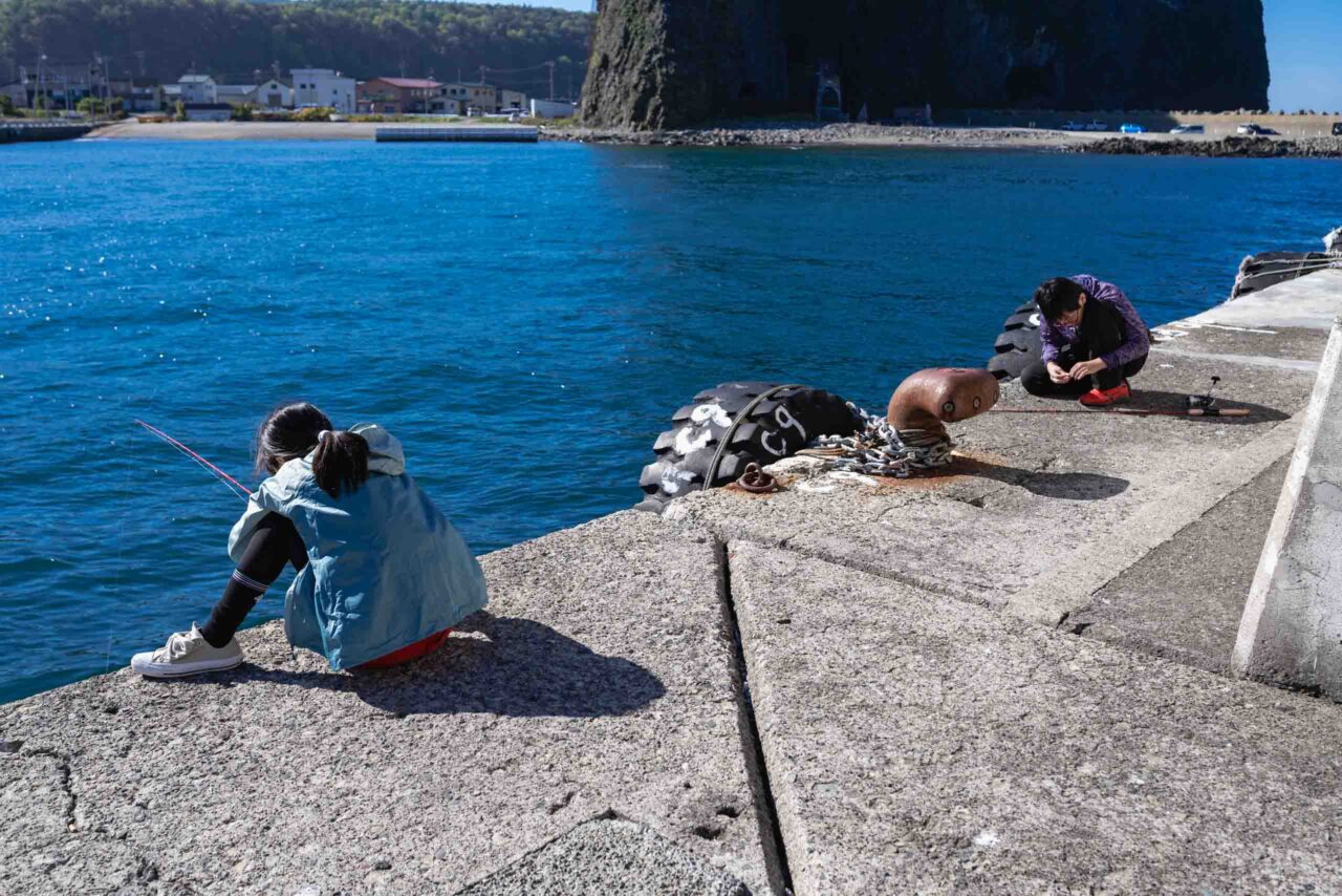 ウトロ漁港で釣りをする小学生と中学生